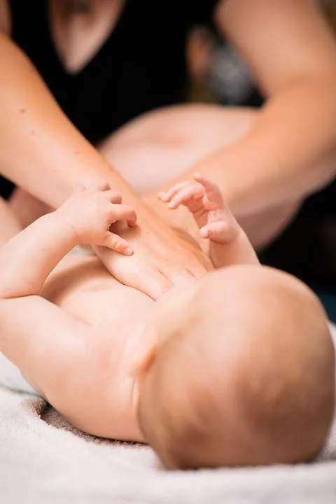 Nahaufnahme einer Babymassage: Hände massieren sanft den Rücken eines Babys