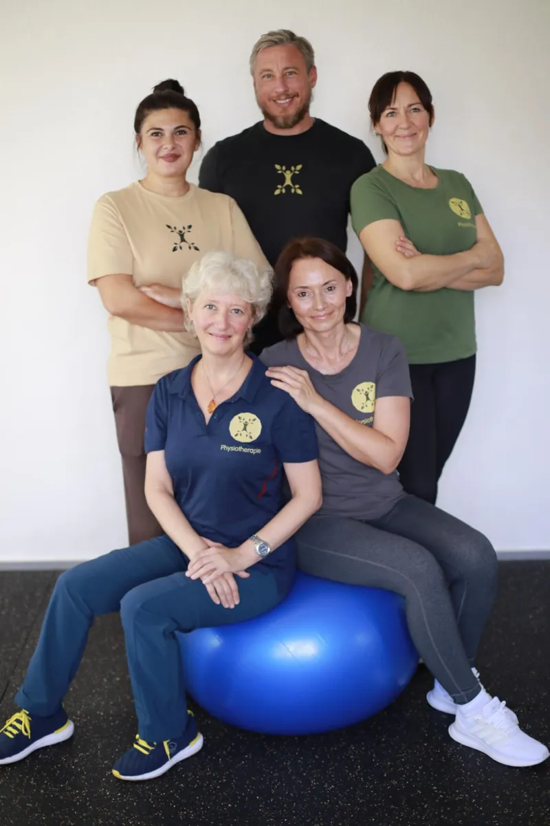 Das fünfköpfige Team der Praxis Pravilo Klaus mit einem blauen Gymnastikball